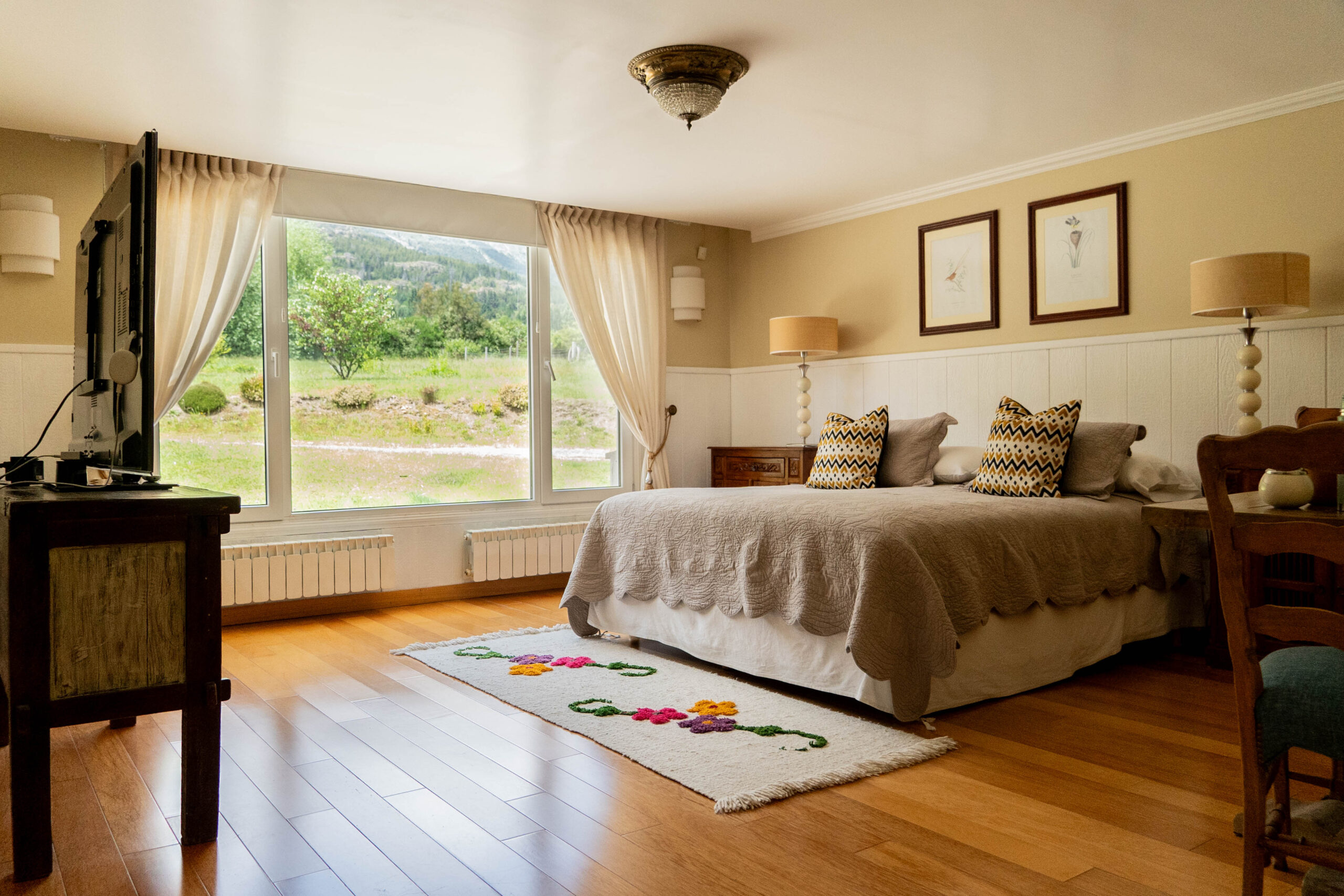 Habitación Deluxe de La Aguada Suite con cama king, TV y ventanal con vista a la montaña, El Bolsón