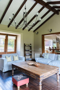 Living con sillones, mesa ratona rústica y techo con vigas en La Aguada Suite, El Bolsón, Patagonia.