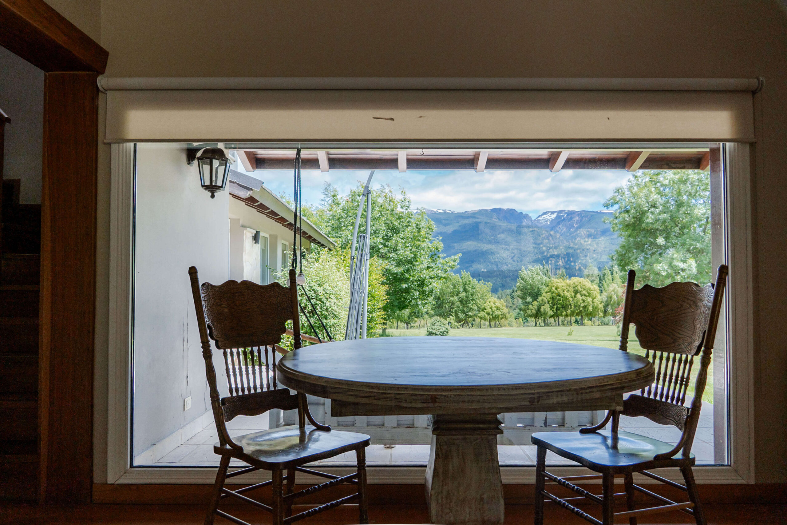 Mesa junto a ventanal con vista al jardín y montañas en La Aguada Suite, El Bolsón, Patagonia. Mesa junto a ventanal con vista al jardín y montañas en La Aguada Suite, El Bolsón, Patagonia.