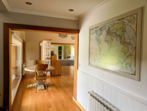 Pasillo interior con piso de madera, marco en madera y decoración mural en La Aguada Suite, El Bolsón, Patagonia.